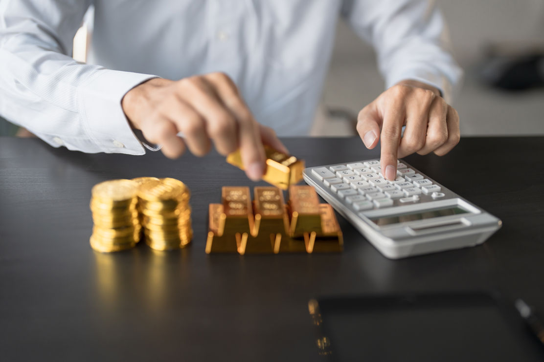 Ein Anleger investiert in Gold und zählt seine physischen Goldbarren und Goldmünzen.