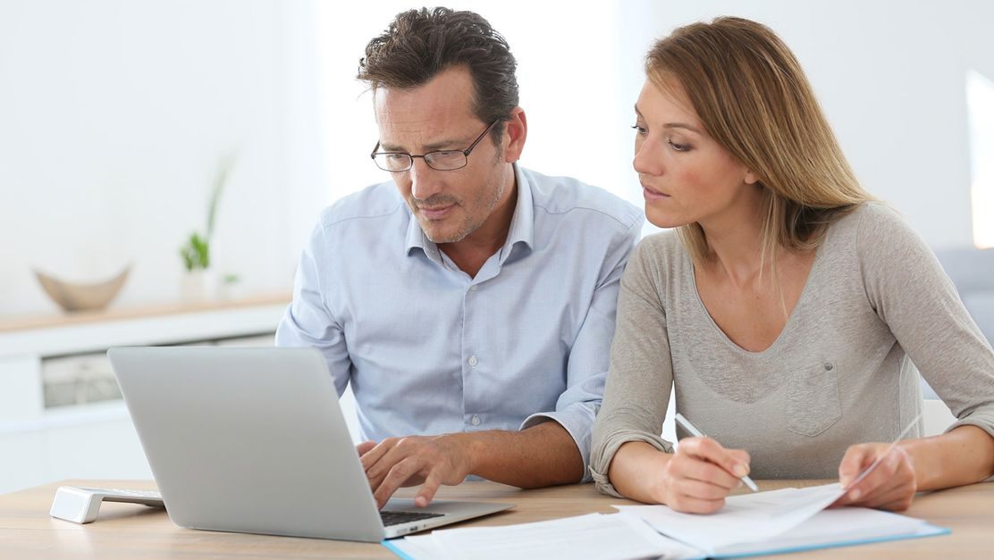 Paar sitzt am Laptop und berechnet mit dem Hypothekenrechner die Hypothek zur Eigenheim-Finanzierung.