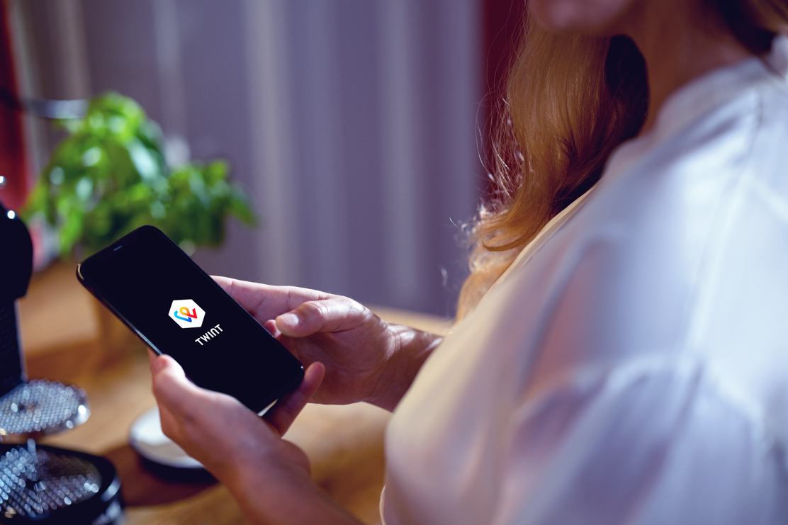 Frau ist zuhause und prüft ihre TWINT App