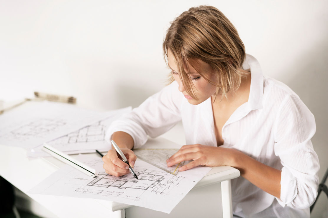 Frau sitzt am Tisch und plant die Architektur im Eigenheim.