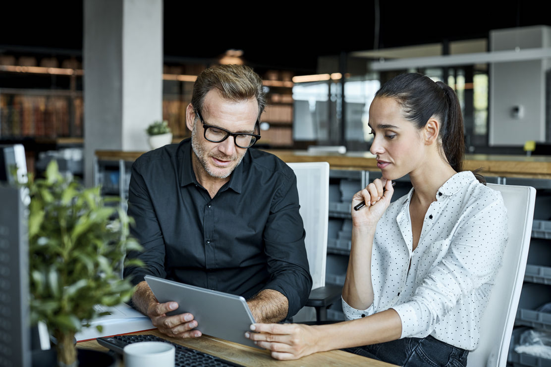 Frau und Mann nutzten ein Tablet, um auf Open Banking Anwendungen zuzugreifen, und arbeiten mit digitalen Finanzlösungen von bLink.